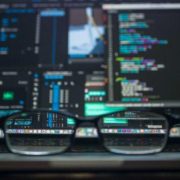 Photo of a pair of glasses in front of several computer screens
