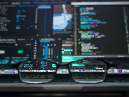 Photo of a pair of glasses in front of several computer screens